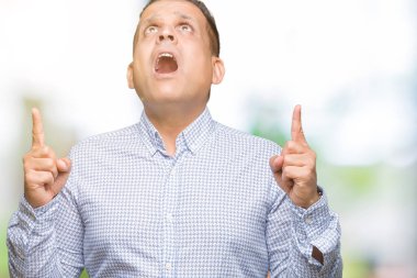 Orta yaş Arap iş adamı izole arka plan üzerinden hayran ve yukarıya bakıp parmakları ile işaret şaşırttı ve silah kaldırdı.