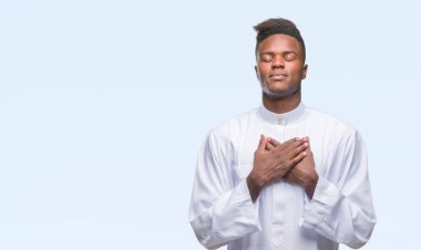 Geleneksel djellaba ile gülümseyen izole arka plan üzerinde giyen genç Arapça Afrika adam kapalı gözler ve yüzünde minnettar jest ile göğüs üzerinde eller. Sağlık kavramı.