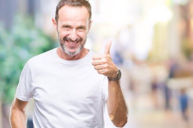Hareketi el ile mutlu yaşasın yapıyor izole arka plan üzerinde beyaz t-shirt giyen orta yaş ağarmış komuta sizde. Kameraya bakarak başarı gösteren ile ifade onaylama.