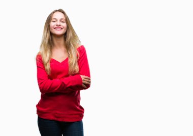 Mutlu yüz ile gülümseyerek kameraya seyir silah geçti arka plan üzerinde kırmızı kazak giyen genç güzel sarışın kadın izole. Olumlu bir kişi.