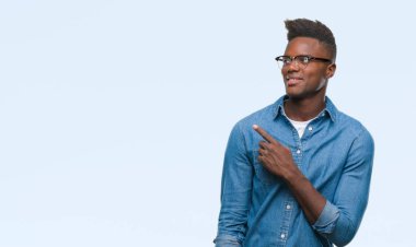 Genç Afro-Amerikan adam izole arka neşeli bir gülümseme ile el ve parmak kadar kameraya bakarak yüzündeki mutlu ve doğal ifade ile yan ile işaret yüz üzerinden.