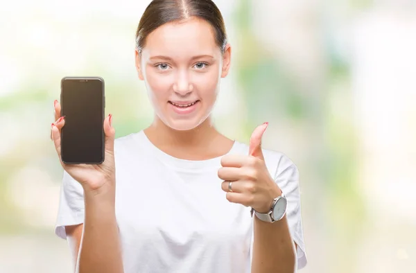 年轻美丽的高加索妇女显示智能手机屏幕在孤立的背景高兴与大微笑做确定的标志 用手指竖起大拇指 优秀的标志 — 图库照片