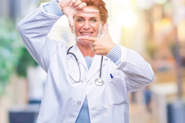 笑顔の幸せそうな顔で指と手作りフレーム分離の背景に医療制服を着て先輩の白人医師女性 創造性と写真のコンセプト — ストック写真