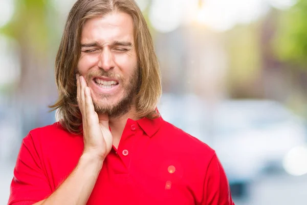 Young handsome man with long hair over isolated background touching mouth with hand with painful expression because of toothache or dental illness on teeth. Dentist concept.