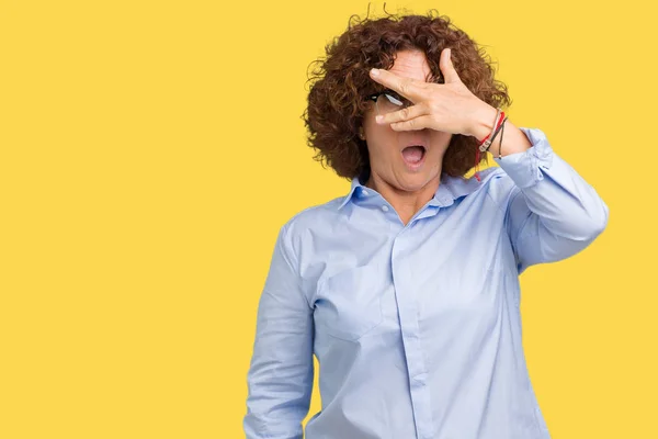 恥ずかしそうな顔で指を探している美しい中間エイガー シニア事業の女性が顔と手で目を覆うショックでピーク分離の背景に眼鏡 — ストック写真