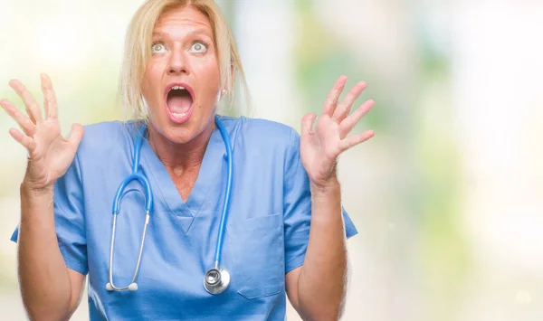 中年金发碧眼的护士医生医生妇女在孤立的背景疯狂和疯狂的喊话和大喊大叫与积极的表情和手臂抬起来 挫折的概念 — 图库照片