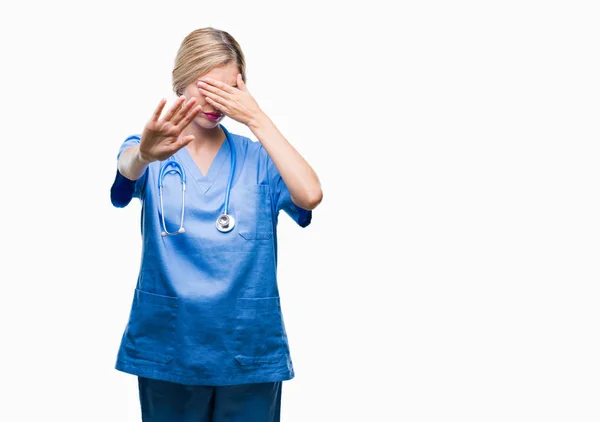 年轻美丽的金发医生护士护士妇女在孤立的背景覆盖眼睛用手和做停止手势与悲伤和恐惧的表情 尴尬和消极的概念 — 图库照片
