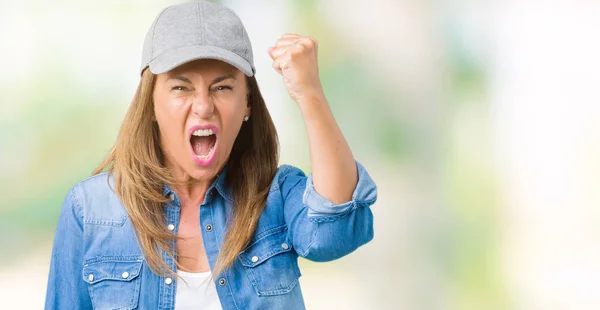 美丽的中年妇女戴着运动帽在孤立的背景愤怒和疯狂的提高拳头沮丧和愤怒 而愤怒地喊 愤怒和进取的概念 — 图库照片