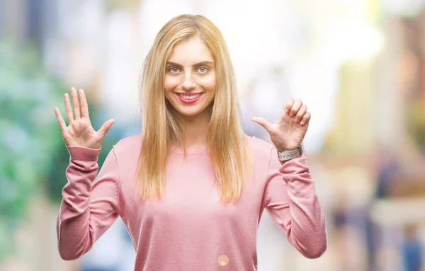 Young beautiful blonde woman wearing pink winter sweater over isolated background showing and pointing up with fingers number six while smiling confident and happy.