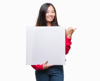 İşaret ve başparmak kadar mutlu yüz gülümseyen tarafı ile gösteren izole arka plan üzerinde afiş tutan Genç Asyalı kadın