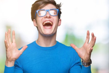 Yakışıklı delikanlı deli ve silah ile başarı için deli kutluyor izole arka plan üzerinde mavi gözlük kaldırdı ve heyecanlı çığlık gözler kapalı. Kazanan kavramı