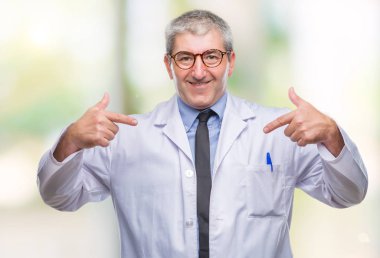 Yüzünde gülümseme ile kendinden emin görünüyorsun, kendini gururlu ve mutlu parmakları ile işaret arka plan üzerinde beyaz önlük giyen bilim adamı profesyonel adam yakışıklı kıdemli Doktor, izole.
