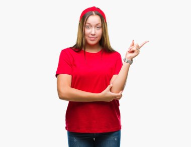 Yüzünde kocaman bir gülümseme ile izole arka plan üzerinde genç Kafkas güzel kadın kameraya bakarak yan el ve parmak ile işaret.