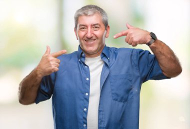 Kendinden emin gösterilen ve işaret parmakları diş ve ağız ile gülümseyen izole arka plan üzerinde yakışıklı komuta sizde. Sağlık kavramı.