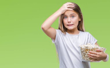 Patlamış mısır snack izole arka plan baş, el ile vurguladı yeme genç güzel kız şok utanç ve sürpriz suratla, öfkeli ve sinirli. Korku ve hata için üzgün.