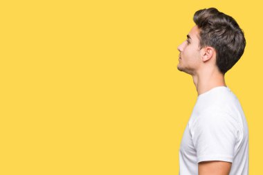 Tarafına, seyir izole arka plan üzerinde beyaz t-shirt giyen genç yakışıklı adam sakin ol kendine güvenen gülümseme ile doğal yüz pozuyla profili.