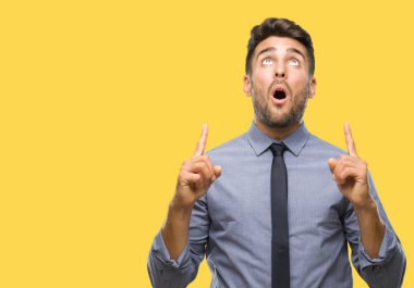 Genç yakışıklı iş adamı izole arka plan üzerinden hayran ve yukarıya bakıp parmakları ile işaret şaşırttı ve silah kaldırdı.