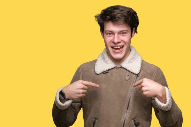Yüzünde gülümseme ile kendinden emin görünüyorsun, kendini gururlu ve mutlu parmakları ile işaret izole arka plan üzerinde kış ceket giyen genç yakışıklı adam.