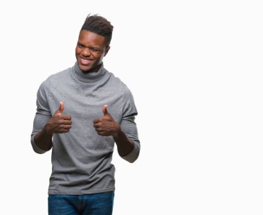 İzole arka plan başarı işareti el ile olumlu hareketi yaparken genç Afro-Amerikan adam başparmak gülümseyen ve mutlu. Neşeli bir ifadeyle, kazanan jest kameraya bakıyor.