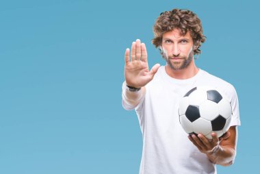 Açık eliyle dur işareti ile ciddi ve kendine güvenen ifade, savunma jest yapıyor izole arka plan üzerinde futbol futbol topu tutan Latin asıllı yakışıklı modeli