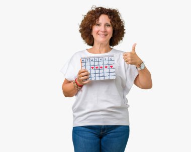 İzole arka plan üzerinde adet takvim ok işareti, başparmak ile parmak, mükemmel işareti yapıyor kocaman bir gülümseme ile mutlu tutan ager üst düzey kadın orta