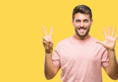 Yakışıklı delikanlı gösterilen ve parmakları ile işaret izole arka plan üzerinde kendinden emin ve mutlu gülümseyerek süre yedi numara.