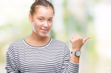 Seyir ve başparmak yanında yukarıyı mutlu yüz ile gülümseyen izole arka plan üzerinde genç güzel bir beyaz kadın.