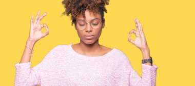 Güzel genç Afro-Amerikan kadın gözlük izole arka plan üzerinde dinlenmek ve gülümseyen gözlerle kapalı parmak jestle meditasyon yapıyor. Yoga kavramı.