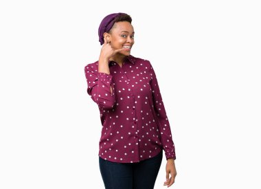 İşin gülümseyen izole arka plan üzerinde başörtüsü giyen güzel genç Afro-Amerikan kadın telefon hareketi ile el ve parmak telefonda konuşuyor gibi. Kavramları iletişim.