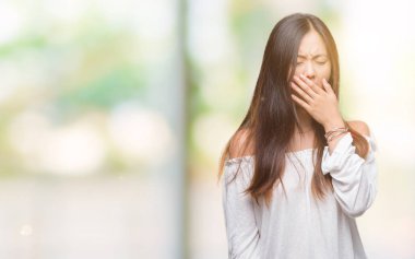 Genç Asyalı kadın izole arka plan üzerinde el ile ağız kapsayan yorgun esneme sıkılmış. Restless ve uyku hali.