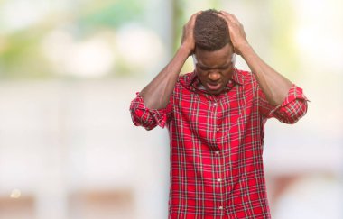 Genç Afro-Amerikan adam çünkü umutsuz ve stresli baş ağrısı acı izole arka plan üzerinde ağrı ve migren. Ellerini kafasına.