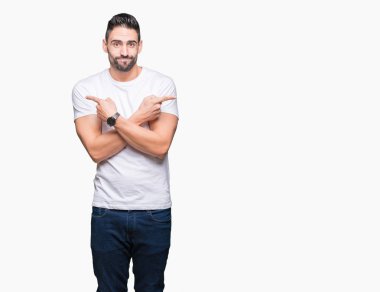 Yakışıklı adam beyaz üzerinde beyaz t-shirt giyen izole arka plan her iki parmak ile işaret eden, farklı yönde katılmıyorum