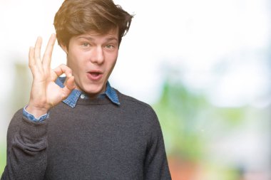 Gülümseyen izole arka plan üzerinde genç yakışıklı zarif adam el ve parmaklar ok işaretiyle yapıyor olumlu. Başarılı ifade.