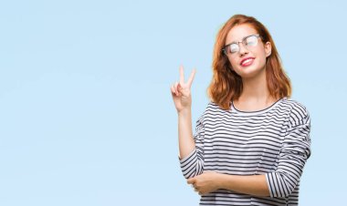 İzole arka plan mutlu yüz zafer işareti yaparken kameraya göz kırpıyor ile gülümseyen gözlüklü genç güzel kadın. İki numaralı.