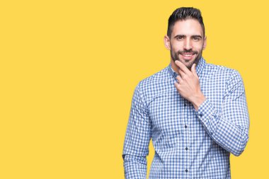 Yakışıklı delikanlı emin çapraz kollar ve çeneme kaldırdı el ile gülümseme ile kameraya bakarak izole arka plan üzerinde. Pozitif düşünce.