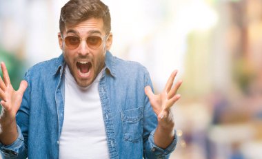 Yakışıklı delikanlı üzerinde güneş gözlüğü takıyor deli kutluyor arka plan izole ve silah ile başarı için yükseltilmiş ve açık gözleri heyecanlı çığlık hayrete düşürdü. Kazanan kavramı