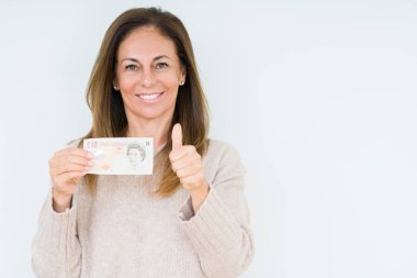 İzole arka plan üzerinde 10 pound banknot ok işareti, başparmak ile parmak, mükemmel işareti yapıyor kocaman bir gülümseme ile mutlu tutan orta yaş kadın