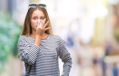 Güneş gözlüğü takıyor bir şey pis ve iğrenç kokulu izole arka plan, dayanılmaz koku, holding nefes burun parmaklar ile genç güzel sarışın bir kadın. Kötü kokuyor kavramı.