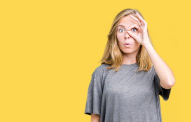 Sürpriz yüz, göz parmaklarının arasından seyir ile ok jest yapıyor izole arka plan üzerinde büyük boy rahat t-shirt giyen güzel genç kadın şok. İmansız ifade.