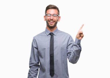 Kameraya bakarak yan el ve parmak ile işaret eden genç yakışıklı iş adamı yüzünde kocaman bir gülümseme ile izole arka plan üzerinde.