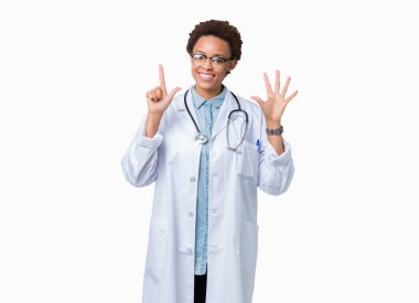 Gösterilen ve parmakları ile işaret izole arka plan üzerinde tıbbi ceket giyen genç Afro-Amerikan doktor kadın kendinden emin ve mutlu gülümseyerek süre yedi numara.