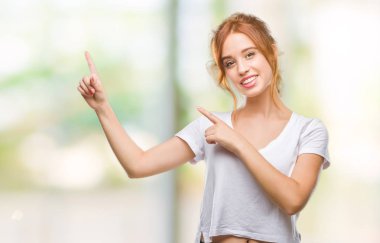 Gülümseyen ve iki elleri ve parmakları ile tarafına işaret kamera bakarak izole arka plan üzerinde genç güzel kadın.