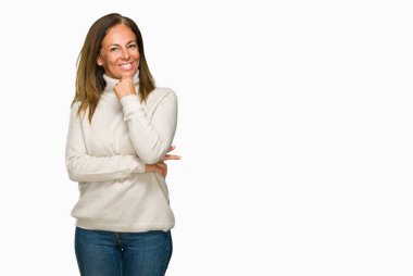 Emin çapraz kollar ve çeneme kaldırdı el ile gülümseme ile kameraya bakarak izole arka plan üzerinde kış kazak giyen güzel orta yaş yetişkin kadın. Pozitif düşünce.