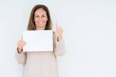 İzole arka plan üzerinde boş kağıt levha ok işareti, başparmak ile parmak, mükemmel işareti yapıyor kocaman bir gülümseme ile mutlu tutan orta yaş kadın