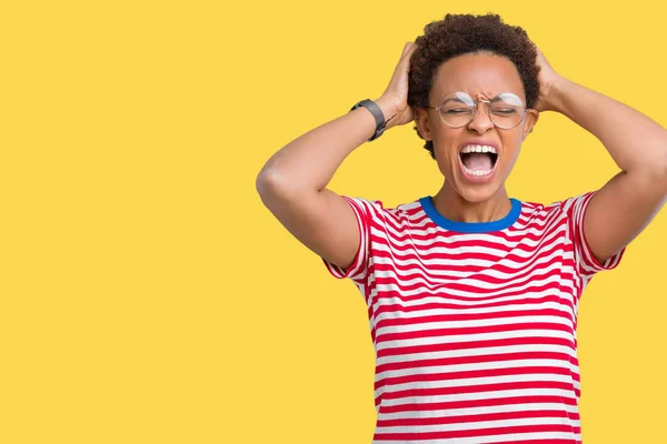 Beautiful young african american woman wearing glasses over isolated background Crazy and scared with hands on head, afraid and surprised of shock with open mouth