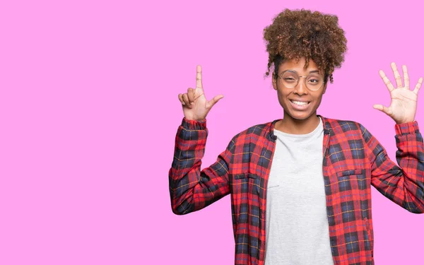 孤立した背景表示と指で上向きに眼鏡をかけて美しい若いアフリカ系アメリカ人女性数は自信を持って 幸せな笑みを浮かべている間 — ストック写真