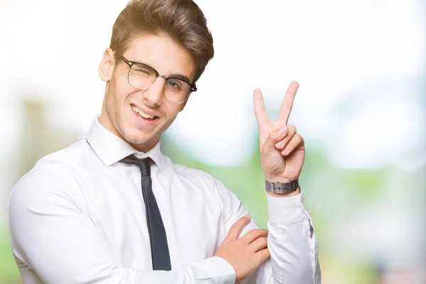 若いビジネスマン勝利のサインを行うカメラでウィンクしている幸せそうな顔を浮かべて隔離された背景にメガネを着用します — ストック写真