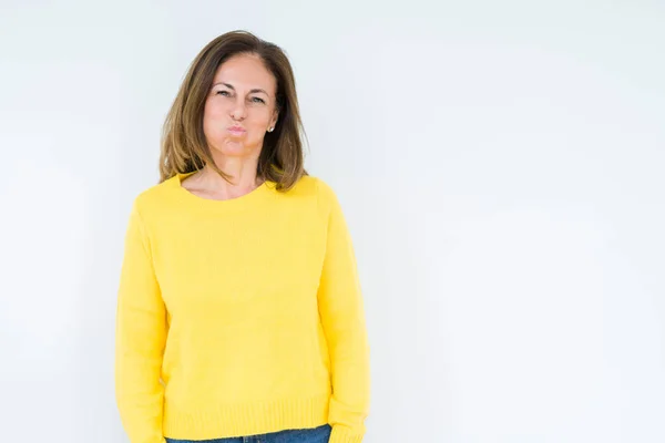 stock image Beautiful middle age woman wearing yellow sweater over isolated background puffing cheeks with funny face. Mouth inflated with air, crazy expression.