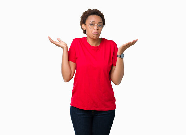 Beautiful young african american woman wearing glasses over isolated background clueless and confused expression with arms and hands raised. Doubt concept.