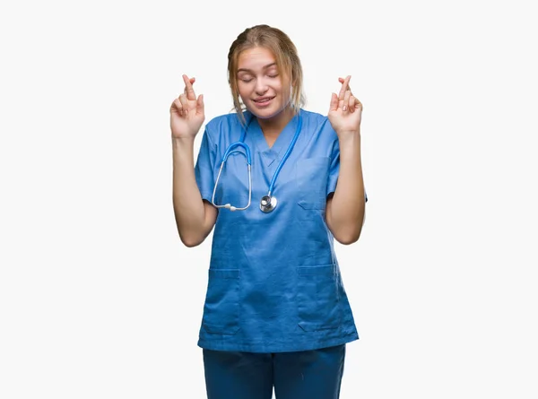 笑顔希望と目の交差指分離の背景の上の外科医の制服を着て若い白人医師女性が閉じられます 運と迷信的な概念 — ストック写真